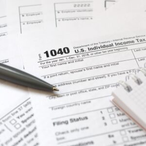 The pen and notebook is lies on the tax form 1040 U.S. Individual Income Tax Return.