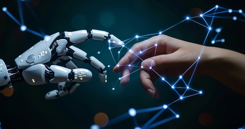 A human hand reaches toward a robotic hand, with glowing blue digital connections linking their fingertips against a dark background.