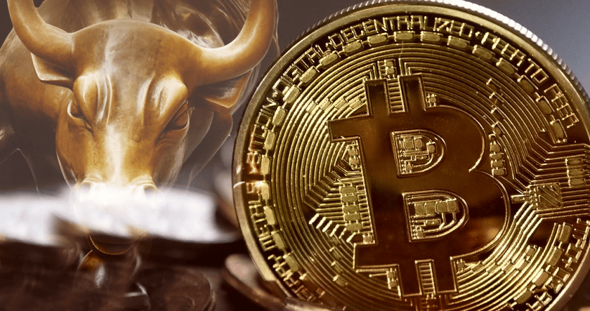 A close-up of a shiny Bitcoin coin in front of a bronze bull statue, symbolizing cryptocurrency and a bullish financial market.