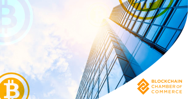 Glass skyscraper with sun glare, overlaid with Bitcoin symbols; Blockchain Chamber of Commerce logo in bottom right corner.