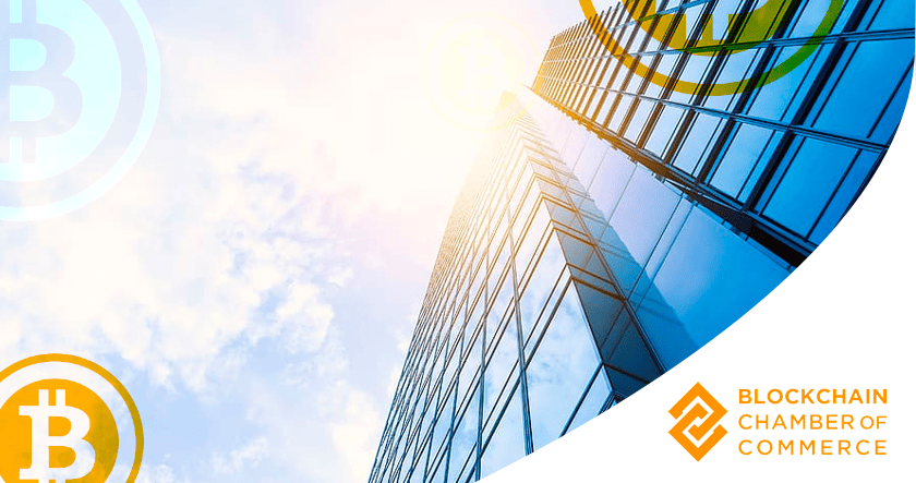 Glass skyscraper with sun glare, overlaid with Bitcoin symbols; Blockchain Chamber of Commerce logo in bottom right corner.