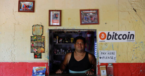A man stands behind a small shop counter with a 