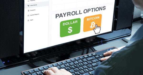 A person selects between dollar and bitcoin payroll options on a computer screen, with a cursor hovering over the bitcoin option.
