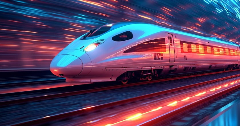 A high-speed bullet train moves quickly along tracks at night, with blurred lights creating a sense of motion.