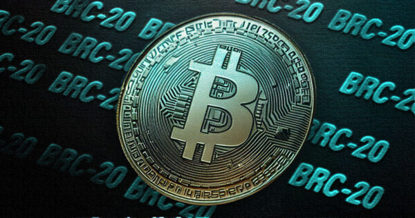 A metallic Bitcoin coin is shown on a surface with repeated 