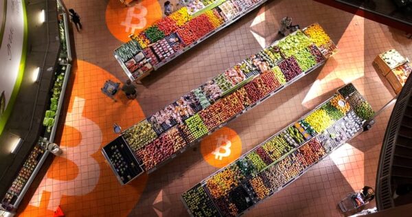 Aerial view of a supermarket produce section with organized fruits and vegetables; orange Bitcoin logos are visible on the floor.