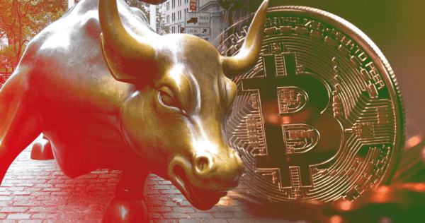 A bronze charging bull statue is shown alongside a large bitcoin symbol, representing bullish sentiment in cryptocurrency markets.