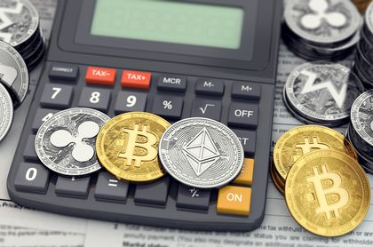 Physical representations of cryptocurrency coins including Bitcoin, Ethereum, and Ripple placed on a calculator with financial documents underneath.