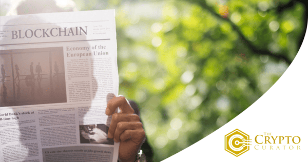 A person holds a newspaper featuring an article on blockchain and the economy of the European Union; 