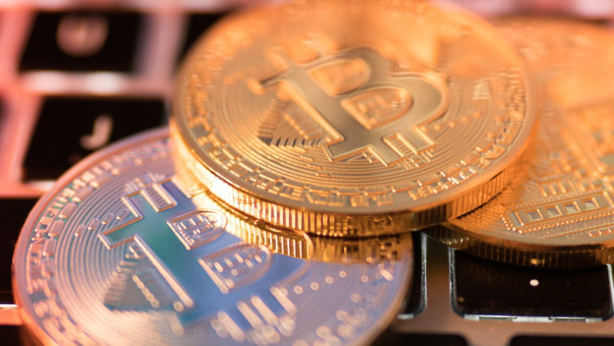 Three physical coins with bitcoin symbols placed on a computer keyboard.