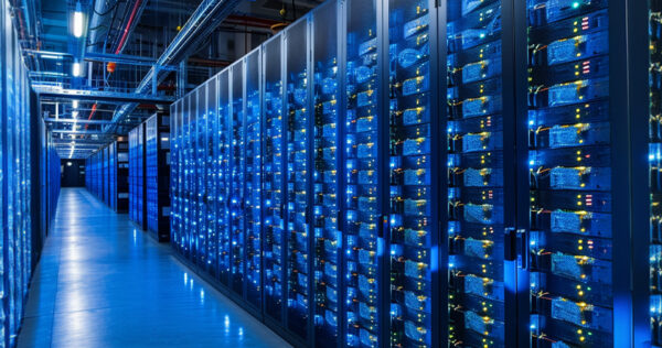 A large data center with rows of server racks illuminated by blue lights, showing network cables and equipment in a modern facility.