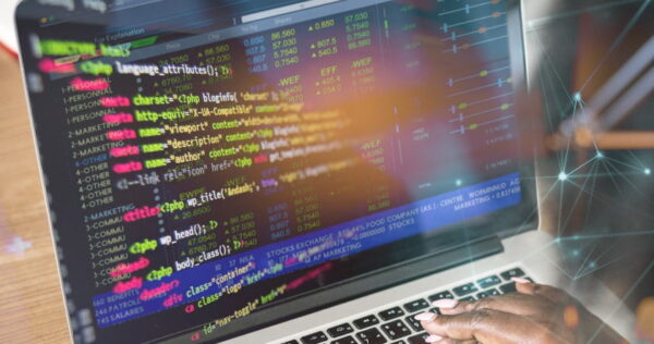 A person types on a laptop displaying colorful lines of HTML code on the screen, with graphical digital effects overlaying the image.