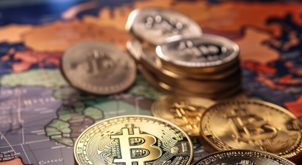 Physical representations of Bitcoin cryptocurrency coins are placed on a world map, suggesting a global concept of digital currency.