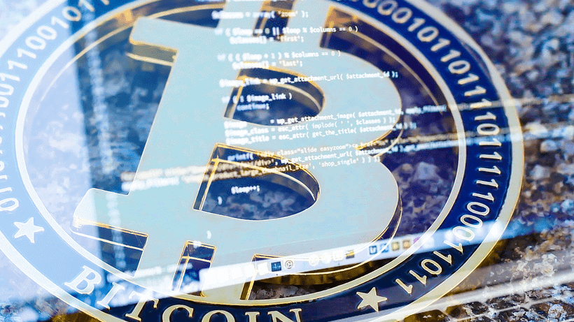 Close-up of a Bitcoin symbol with computer code superimposed, representing cryptocurrency technology and digital finance.