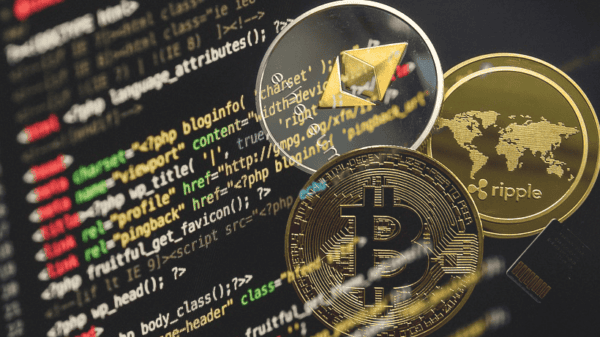 Three cryptocurrency coins (Bitcoin, Ethereum, Ripple) are shown overlaid on a background of computer code on a screen.
