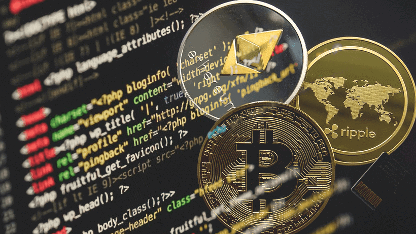 Three cryptocurrency coins (Bitcoin, Ethereum, Ripple) are shown overlaid on a background of computer code on a screen.