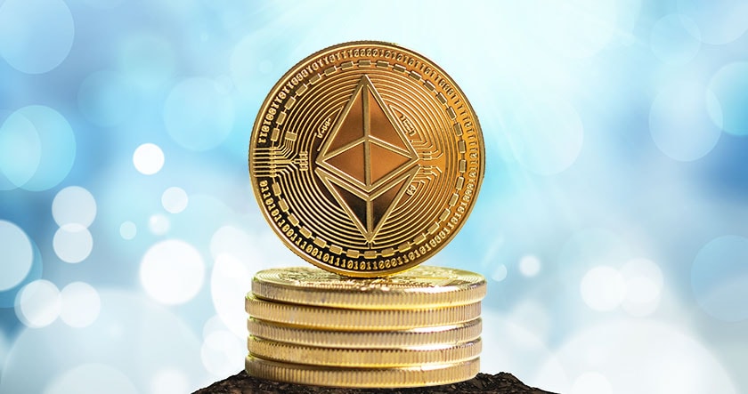 A stack of gold-colored coins with a larger Ethereum coin on top, displaying the Ethereum logo, against a blue bokeh background.