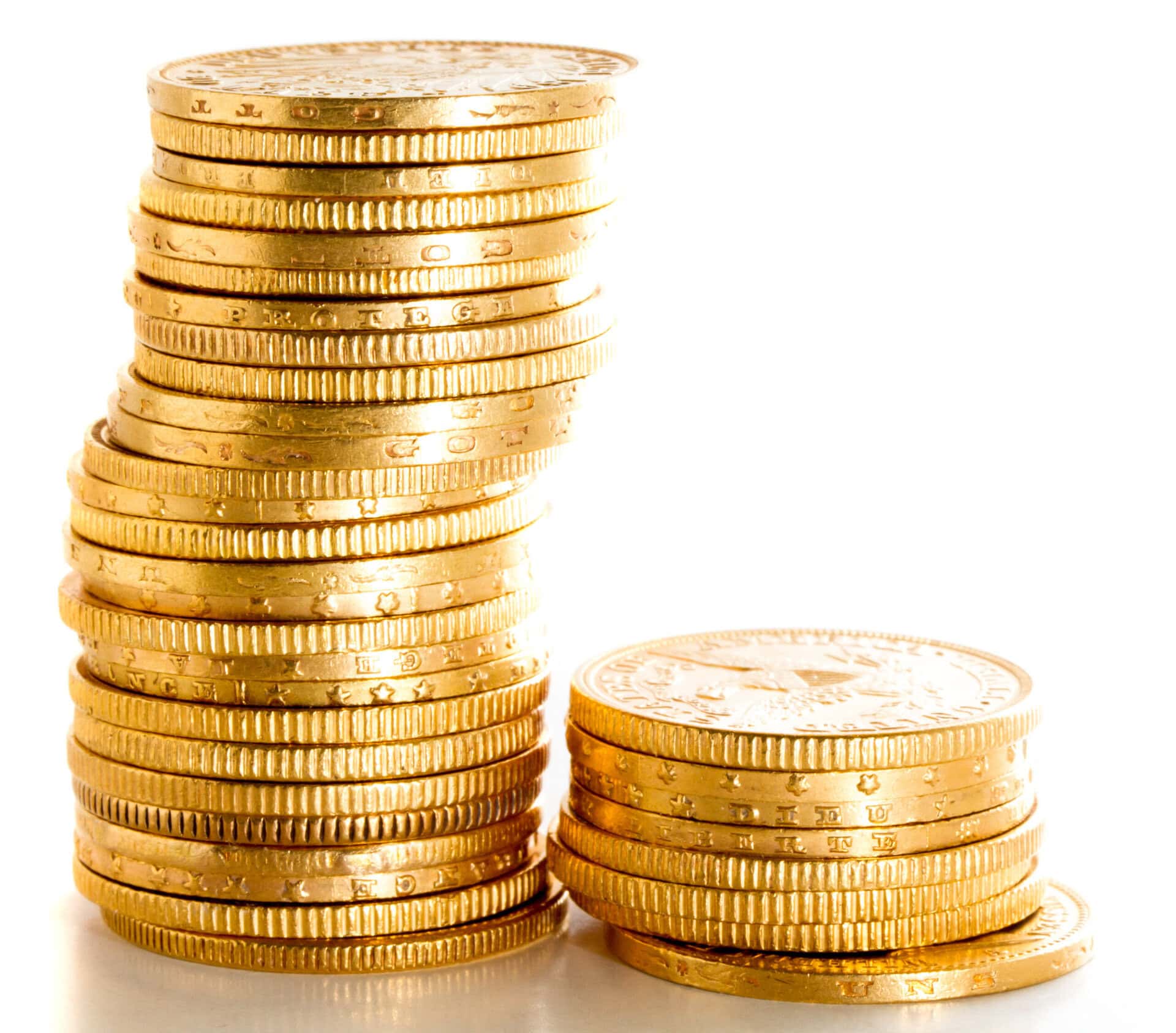 A tall, slightly leaning stack of shiny gold coins stands next to a shorter stack of similar coins, both on a white surface with a bright background.