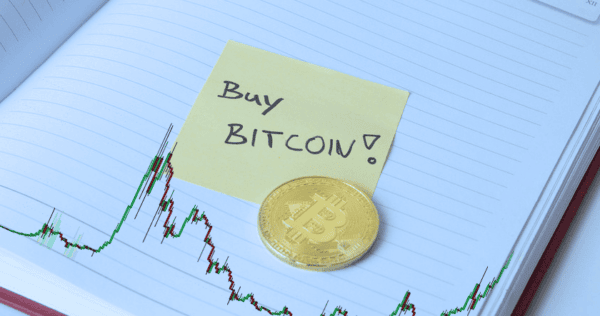 A gold Bitcoin coin and a sticky note with 