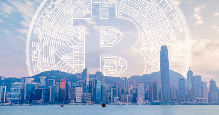 Hong Kong city skyline with a large, digital Bitcoin symbol superimposed in the sky above the skyscrapers.