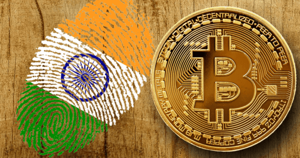 An Indian flag fingerprint and a Bitcoin coin are placed side by side on a wooden surface.