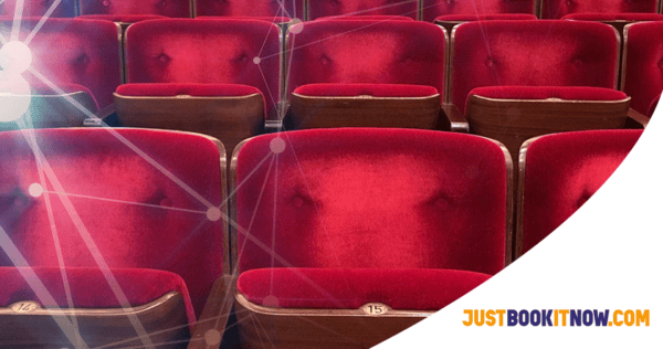 Rows of empty red velvet theater seats with wooden armrests; a white arc and 