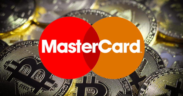 Mastercard logo overlaid on a background of multiple physical Bitcoin coins.