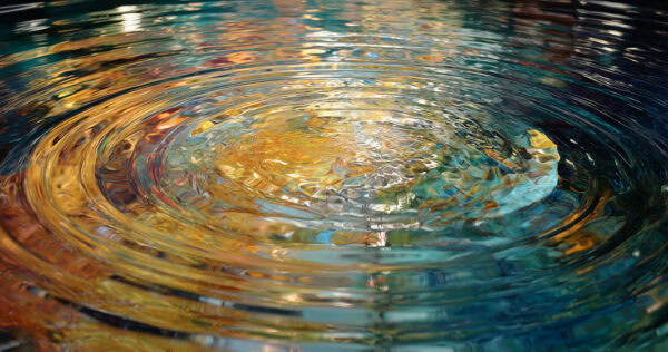 Circular ripples spread across the surface of water, reflecting various colors including blue, gold, and orange.
