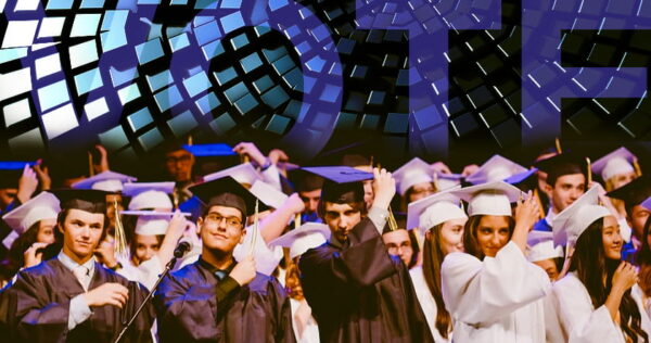 A group of graduates in caps and gowns stands together on stage, adjusting their tassels, with a digital 