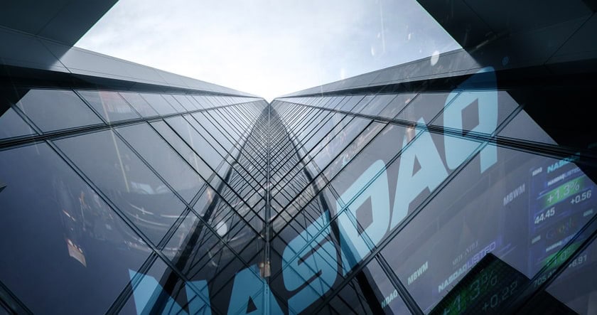 A low-angle view of a tall glass building with the word "NASDAQ" reflected, indicating a financial or stock market setting.