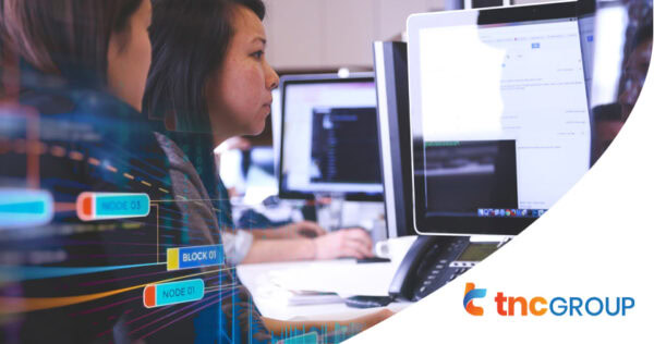 Two people work at computer monitors in an office setting; digital interface graphics and the 