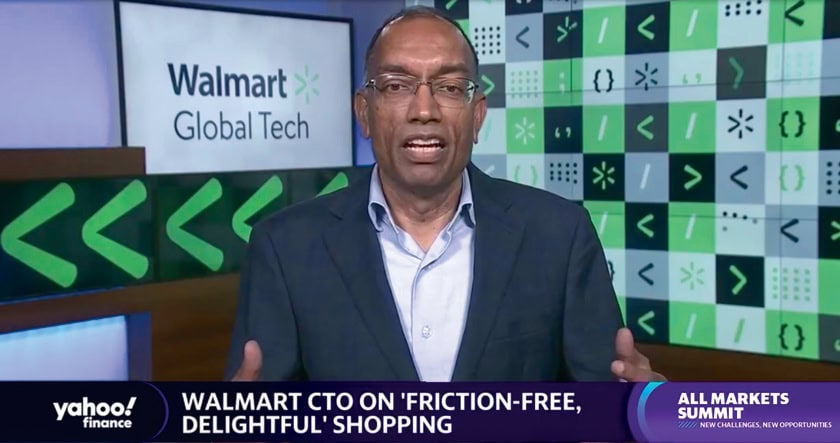 A man in a suit speaks during a Yahoo! Finance segment, with “Walmart Global Tech” and digital icons in the background, discussing friction-free shopping at the All Markets Summit.