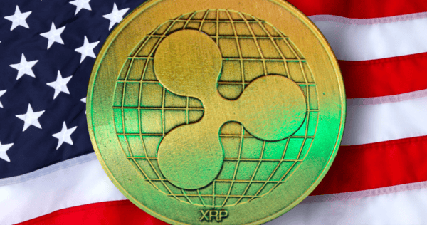 A gold XRP coin with a globe design is shown in front of a United States flag background.